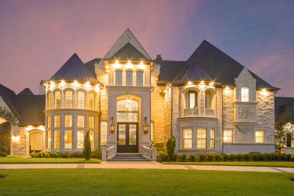 Custom stone home with illuminated architectural details at dusk